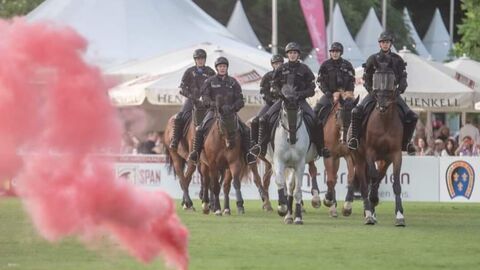 Die Polizeireiterstaffel, sechs Reiterinnen auf Polizeipferden, im Vordergrund steigt roter Rauch auf