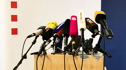 Rednerpult mit Mikrofonen vor Stellwand