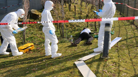 Polizeibeamte in weißen Spurenschutzanzügen sichern Spuren am Tatort