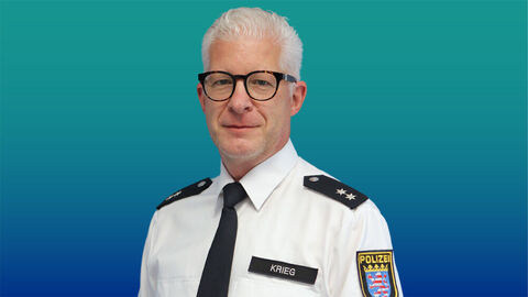 Polizeibeamter mit grauen Haaren und Brille im weißen Diensthemd mit Krawatte