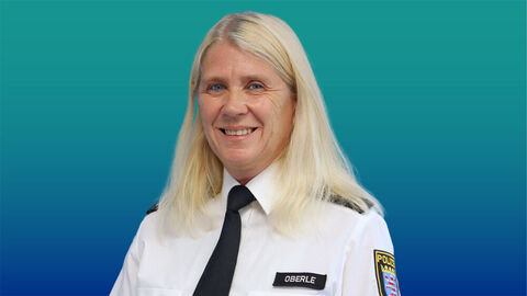 Polizeibeamtin mit langen blonden Haaren im weißen Diensthemd mit Krawatte