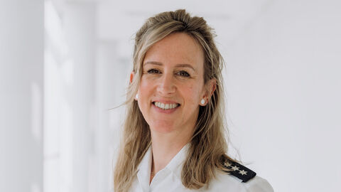 Nicole Cuppens in weißem Uniformhemd und hellem Hintergrund