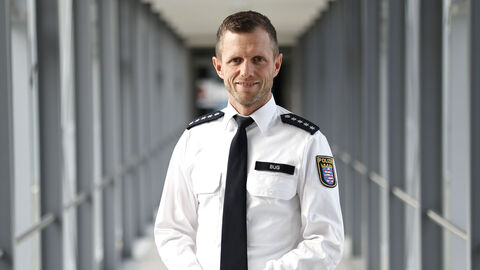 Polizist in weißem Uniformhemd in einem langen Glasdurchgang