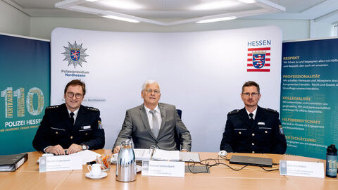 Polizeiliche Kriminalstatistik 2024 des Polizeipräsidiums Nordhessen; Auf dem Bild zu sehen sind von links nach rechts Ltd. PD Lindenborn in Uniform, Polizeipräsident Stelzenbach in ziviler Kleidung und PR Bartoldus in Uniform an einem Tisch sitzend, im Hintergrund eine Präsentationswand mit dem Polizeistern und der Hessenmarke, daneben Aufsteller mit dem Logo Polizei Hessen und 110