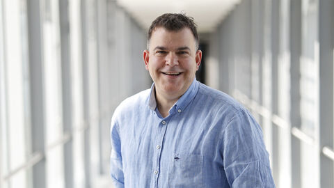 Ein Kollege mit blauem Hemd in einem langen Glasdurchgang