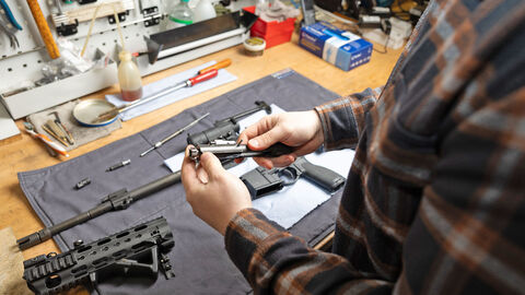 Büchsenmacher arbeitet an einer Waffe an seinem Arbeitstisch