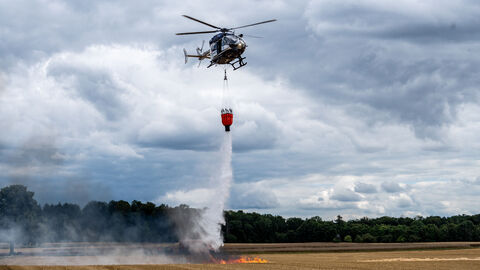 Polizeihubschrauber mit Bambi-bucket beim Feuerlöschen