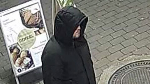 Foto des unbekannten Täters nach bewaffneten Raubüberfall auf Lebensmittelmarkt in Kassel-Waldau; Foto zeigt den Täter von schräg oben auf dem gehweg, bekleidet mit schwarzer Daunenjacke mit Kapuze, einer graue Hose und schwarzen Turnschuhe