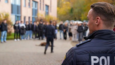 Ein Polizeibeamter von hinten vor zahlreichen Teilnehmerinnen und Teilnehmern bei der Betriebserkundung im Polizeipräsidium Südhessen
