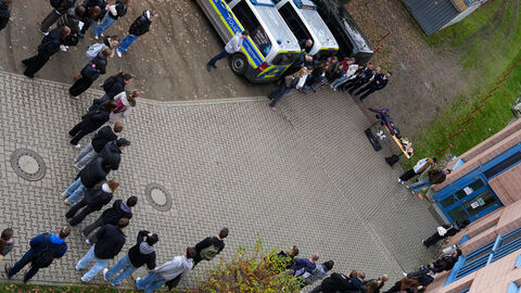 Im Kreis vor Polizeifahrzeugen stehen die Teilnehmerinnen und Teilnehmer zur Vorführung der Diensthundstaffel