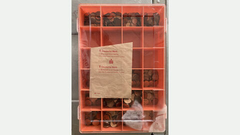 Aufgefundene Kassette; Bild der Kassette in Farbe rot mit Münzen in verschiedenen Fächern sortiert mit einer Geldbanderole auf dem Deckel 