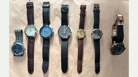 Aufgefundene Uhren; Das Bild zeigt sieben analoge Uhren mit Leder- oder Metallarmband nebeneinander auf einem Tisch aufgereiht