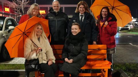 Verschiedene Vertreterinnen und Vertreter des Polizeipräsidiums Westhessen und von Zonta Wiesbaden an der orangen Bank vor dem Polizeipräsidium Westhessen