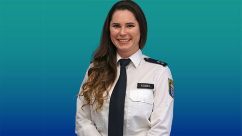 Polizeibeamtin mit dunklen Haaren im weißen Diensthemd mit Krawatte