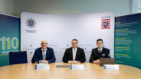 Polizeiliche Kriminalstatistik 2025 für Nordhessen vorgestellt; Drei Personen sitzen nebeneinander an einem Tisch, im Hintergrund ist eine Präsentationswand aufgestellt