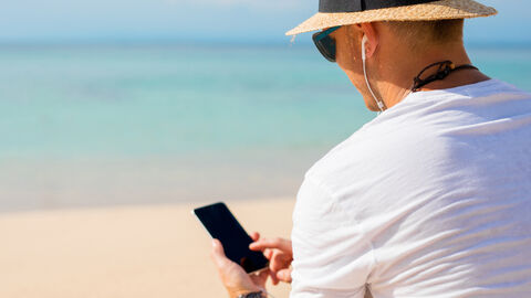 Urlauber am Strand mit Smartphone in der Hand 