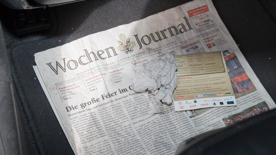 Eine gefaltete Zeitung mit dem Schriftzug Wochen Journal, darauf liegt zerknülltes Papier und ein gefalteter Werbeflyer