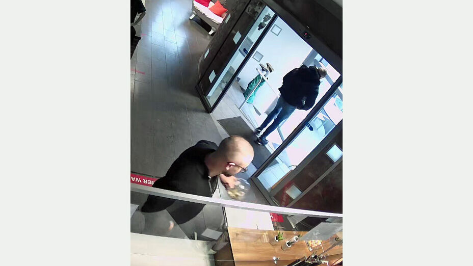 Räuberischer Diebstahl in Kassel; Auf dem Bild sind zwei unbekannte männliche Personen zu sehen, eine Person steht am Verkaufsthresen und die andere verlässt das Geschäft